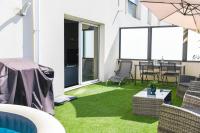 d&#39;une terrasse avec de la pelouse verte, une table et des chaises. dans l&#39;établissement Le Capé-Grand appartement avec terrasse et jacuzzi, à Marseille