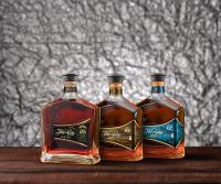 tre bottiglie di whisky sedute su un tavolo di The Lighthouse Retreat, Little Corn island, Nicaragua a Little Corn Island