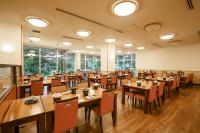 un ristorante con tavoli e sedie in legno e finestre di KAMENOI HOTEL Kanonji a Kanonji