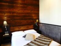a bedroom with a white bed with a wooden wall at Logis Hotel Des Bains in Gérardmer