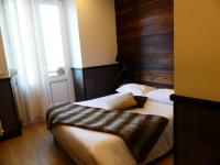 a bedroom with two beds and a large window at Logis Hotel Des Bains in Gérardmer