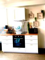eine Küche mit weißen Schränken und einem schwarzen Backofen in der Unterkunft maison entièrement rénovée centre de Luché pringé in Luché-Pringé