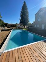 a swimming pool with a wooden deck next to a house at Maison piscine Lot in Laburgade