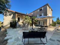 a patio with chairs and an umbrella in front of a building at Maison piscine Lot in Laburgade