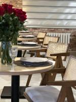 Una hilera de mesas y sillas con un jarrón de rosas rojas. en Jansyn Hotel Restaurant, en Karakol