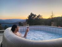 a man in a hot tub with a glass of wine at Maison LGBT des Monts Bleus in Saint-Roman-de-Tousque