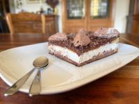 a piece of cake on a white plate with a spoon at Maison LGBT des Monts Bleus in Saint-Roman-de-Tousque