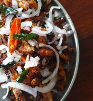 瓦尔卡拉The Ixora - A Boutique Homestay的桌子上放着一碗食物，里面有洋葱和蔬菜。