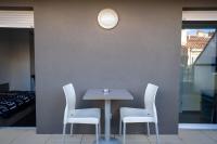 a table with white chairs and a clock on a wall at Le Stratège in Marseille