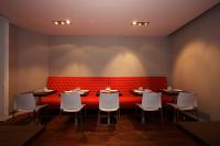 un restaurant avec des tables, des chaises blanches et un banc rouge dans l&#39;établissement Hôtel Henri IV, à La Rochelle