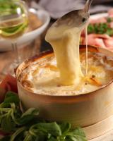 Uma colher está despejando molho em uma tigela de comida. em Race & Rooms em Francorchamps