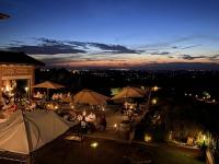 een groep mensen die 's nachts aan tafels onder paraplu's zitten bij Prime Alture Wine Resort in Casteggio