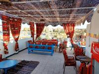a restaurant with red chairs and tables and a view at Gamal Robob Nubian Guest House in Aswan