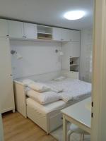a white bedroom with a bed and a table at Fenix studio apartment, Zagreb in Zagreb