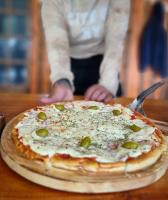 una pizza con olive e formaggio su un tavolo di Hostería Punta Sur en Lago del Desierto no Chalten a El Chalten