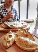 una persona seduta a un tavolo con una pizza di Hostería Punta Sur en Lago del Desierto no Chalten a El Chalten