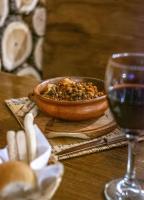 un tavolo in legno con ciotola di cibo e un bicchiere di vino di Hostería Punta Sur en Lago del Desierto no Chalten a El Chalten