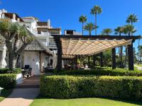 a pergola in front of a house with palm trees at ALCAZABA beach in Estepona