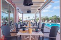 Un patio con mesas y sillas junto a una piscina. en Hotel Sa Barrera - Adults Only, en Cala'n Porter