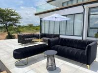 zwei schwarze Ledersofas und ein Sonnenschirm auf einer Terrasse in der Unterkunft Nandoni Waterfront Resort in Thohoyandou