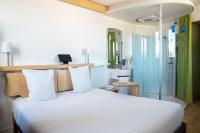 Un dormitorio con una cama blanca y una ducha. en Nomad Hotel le Havre Centre Gare, en Le Havre