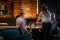 a woman standing at a table in a restaurant at Velvet Hotel Manchester, WorldHotels Crafted in Manchester