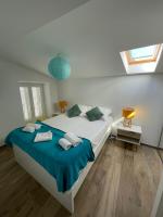 a white bedroom with a large bed with blue sheets at Duplex en plein centre in Propriano