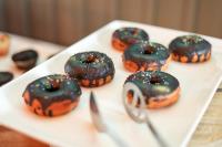 un plato blanco con donuts de chocolate en una mesa en Regenta Place Jhansi by Royal Orchid Hotels Limited, en v