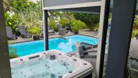 a jacuzzi tub on a patio next to a pool at Villa de 3 chambres avec piscine privee jacuzzi et jardin clos a Baie Mahault in Baie-Mahault