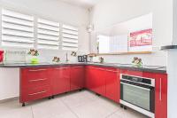 a red kitchen with white walls and windows at Villa de 3 chambres avec piscine privee jacuzzi et jardin clos a Baie Mahault in Baie-Mahault
