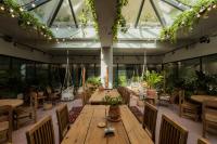a conservatory with wooden tables and chairs and plants at Khedi Hotel Tbilisi in Tbilisi City