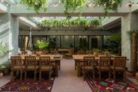 a restaurant with wooden tables and chairs and plants at Khedi Hotel Tbilisi in Tbilisi City