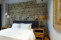 a bedroom with a white bed and a stone wall at Khedi Hotel Tbilisi in Tbilisi City