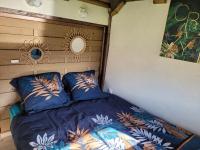 a bed with blue comforter and pillows in a room at La paillote idyllique in Faverolles-sur-Cher