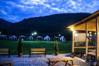 a patio with benches and a green field with tents at Green Resort Suncuius in Şuncuiuş