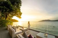 a woman in a white dress standing on a deck near the water at Amari Phuket in Patong Beach
