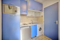 a small kitchen with blue cabinets and a washing machine at Very pleasant 2 rooms garage near the beaches in Cannes