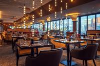 a restaurant with tables and chairs and large windows at Hyatt Regency Dusseldorf in Düsseldorf