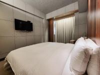 a bedroom with a white bed and a flat screen tv at CHECK inn Express Taichung Fengchia in Taichung