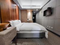 a bedroom with a bed and a tv and a couch at CHECK inn Express Taichung Fengchia in Taichung