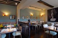 een eetkamer met tafels en stoelen en een portret van een vrouw bij Crown and Castle in Orford