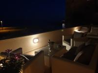 a balcony with chairs and a table at night at Villa Ana Apartments in Mlini
