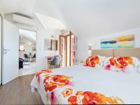 a white bedroom with a large bed with flowers on it at Villa Ana Apartments in Mlini