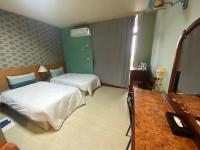 a hotel room with two beds and a desk at Jiuning Business Hotel in Tainan