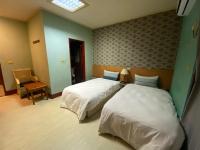 a hotel room with two beds and a window at Jiuning Business Hotel in Tainan