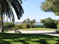 two benches in a park with palm trees and the ocean at Appartement Six-Fours-les-Plages, 2 pièces, 5 personnes - FR-1-316-118 in Six-Fours-les-Plages