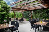 Un patio con mesas y sillas bajo una pérgola de madera. en Pension Pfefferstübchen, en Brotterode