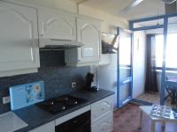 a kitchen with white cabinets and a black cat sitting on the stove at Vue Mer 180° Parking+Lave-Linge+Proche Plages+Piscine in Cap d&#39;Agde