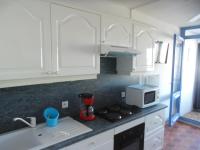 a kitchen with white cabinets and a stove and a microwave at Vue Mer 180° Parking+Lave-Linge+Proche Plages+Piscine in Cap d&#39;Agde