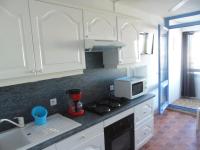 a kitchen with white cabinets and a stove and a microwave at Vue Mer 180° Parking+Lave-Linge+Proche Plages+Piscine in Cap d&#39;Agde